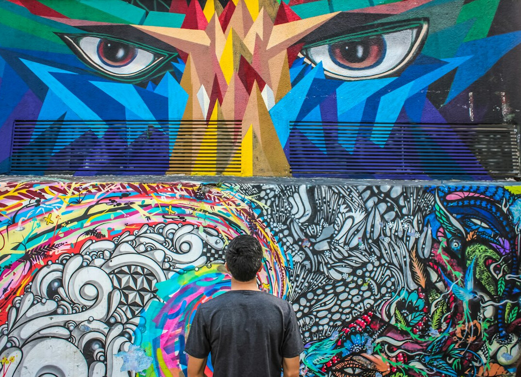 Young Chilean street muralist standing next to his artwork