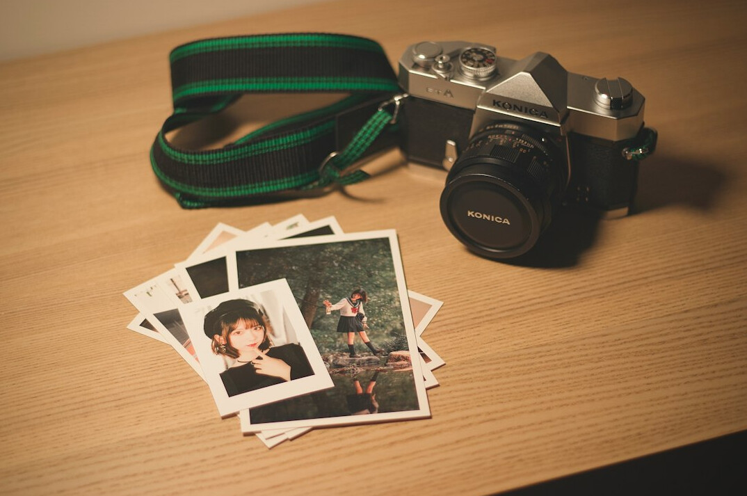 Desk with printed photographs, contact sheets and a film camera